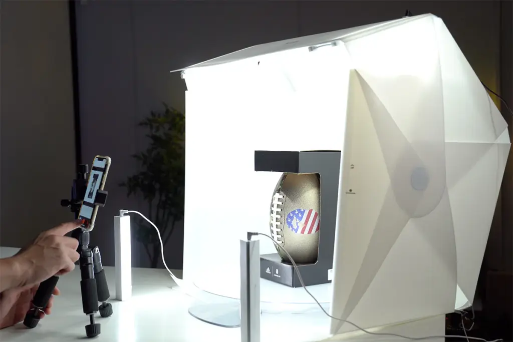 A product being photographed inside a lightbox with a camera on a tripod.