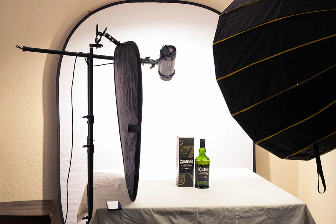 A product photography setup featuring a bottle of Ardbeg whisky with studio lighting and a white backdrop