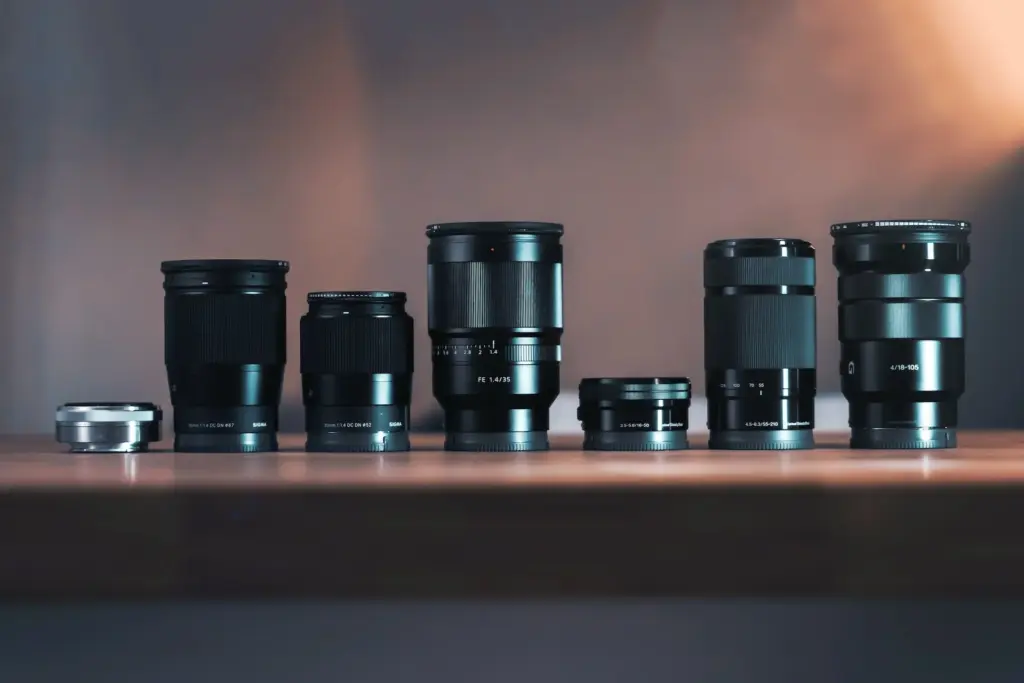 A row of various camera lenses arranged on a wooden surface.