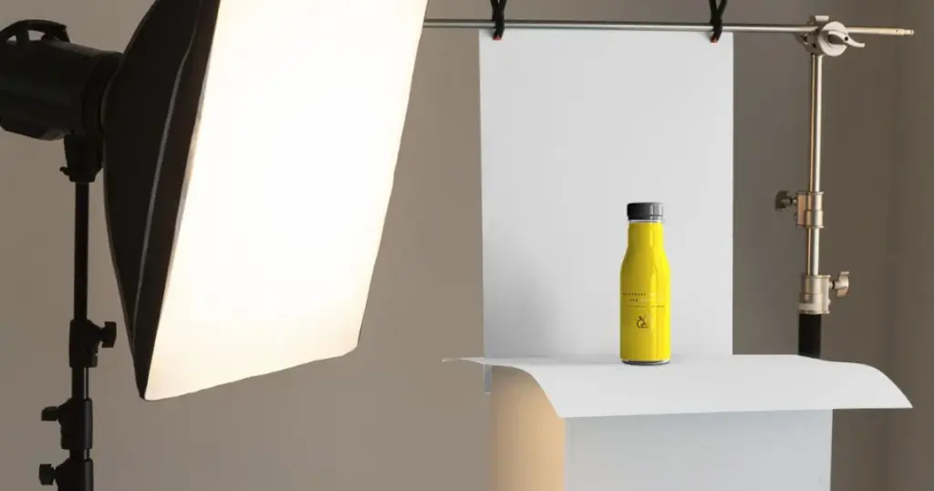 Product photography setup with a yellow bottle placed on a white backdrop, illuminated by soft lighting.