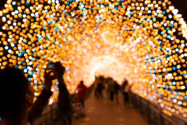 A blurry photo of a person capturing a light tunnel with bokeh lights in the background.