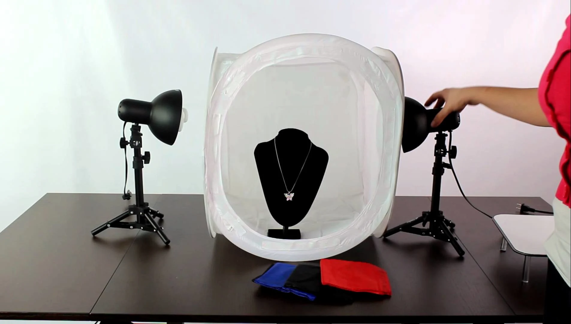 Jewelry photography setup with a lightbox, jewelry stand, and lighting equipment.