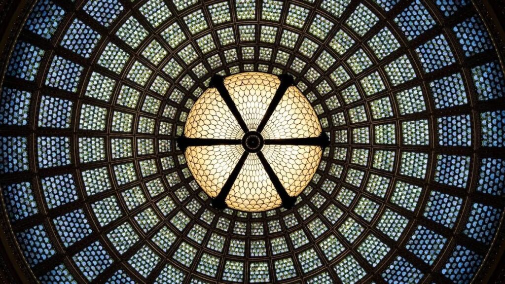 Overhead shot of a stained glass dome with geometric patterns and vibrant colors.