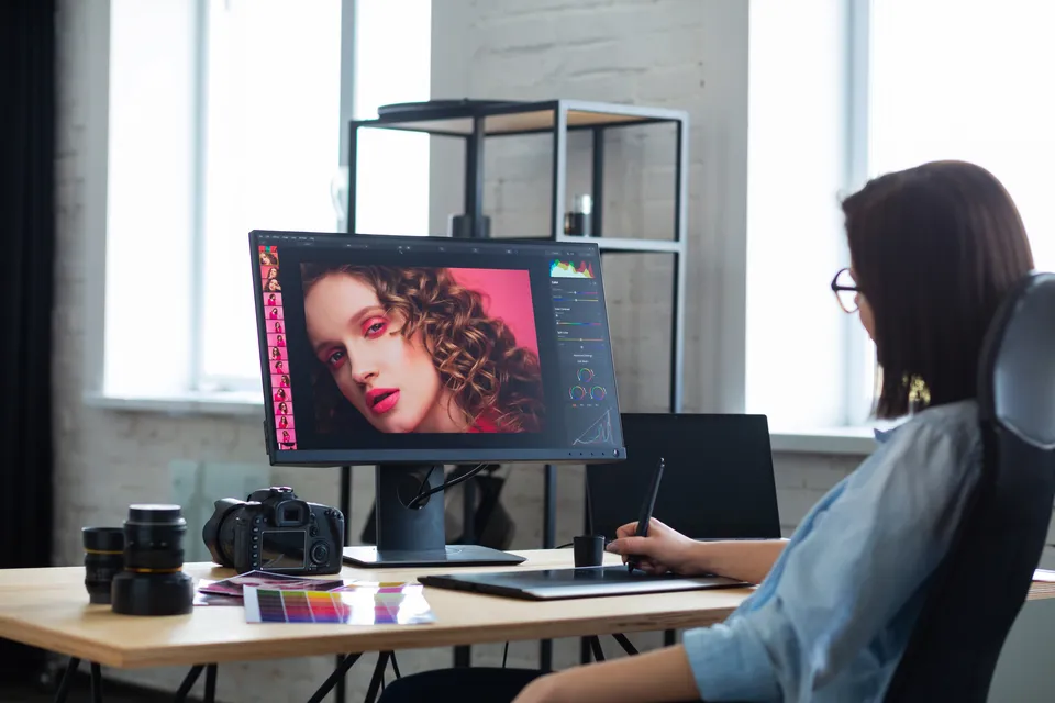 Person editing a portrait photo on a computer with a graphic tablet in a creative workspace.