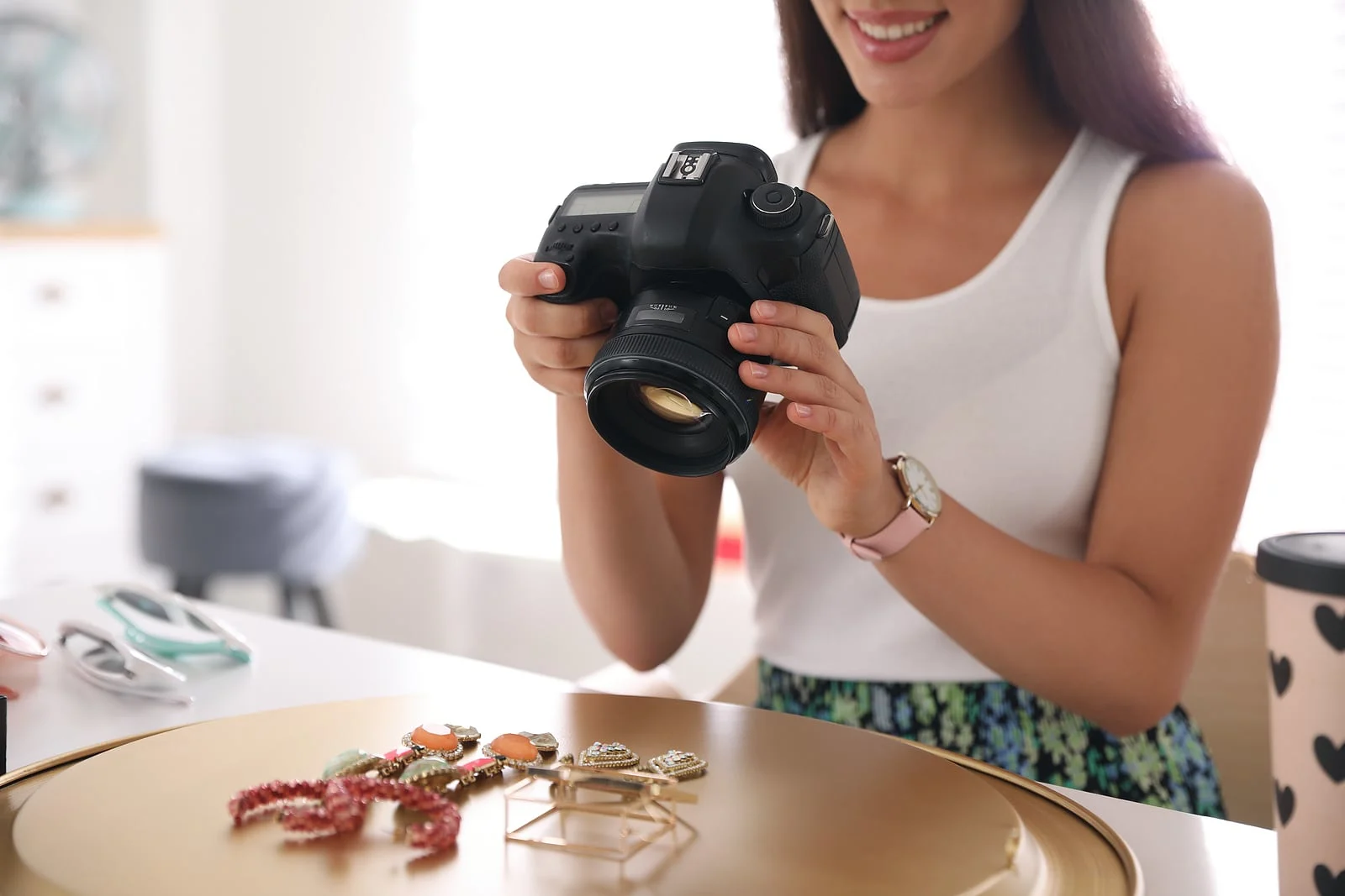 Person photographing jewelry with a DSLR camera, with colorful pieces displayed on a table.