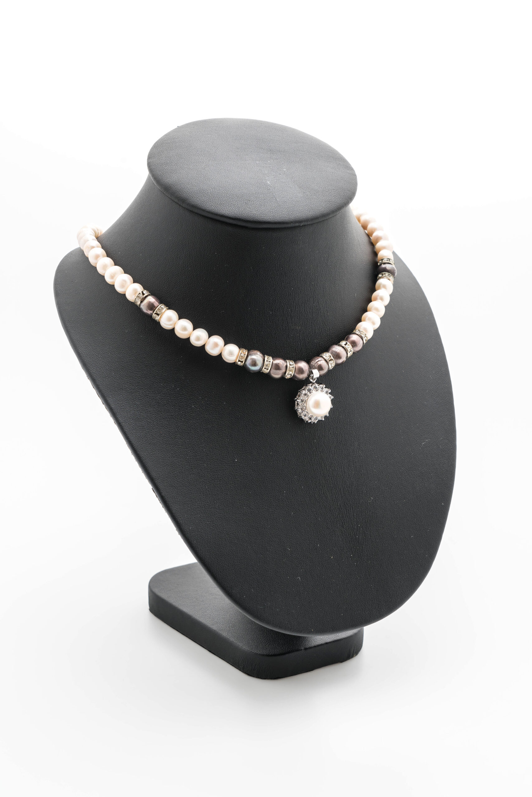 Elegant pearl necklace with a silver pendant on a black display stand