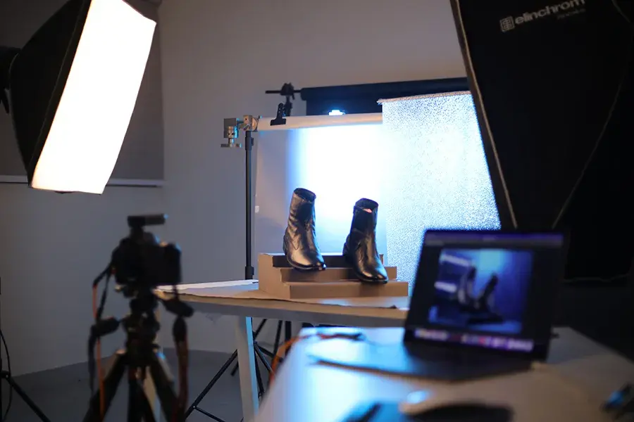 Product photography setup with softbox lighting, backlight for shoes, and laptop for tethered shooting.