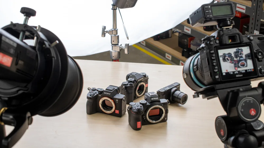 a few cameras placed on a wooden surface and being photographed
