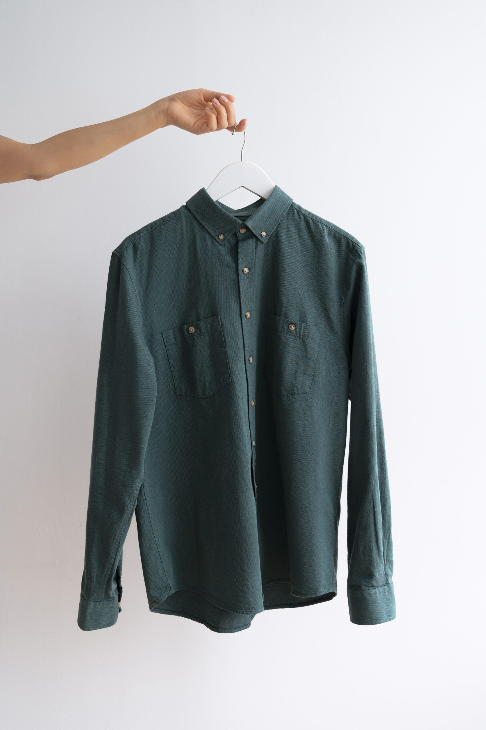Green long-sleeve shirt being held up, showcasing its design and fabric texture.
