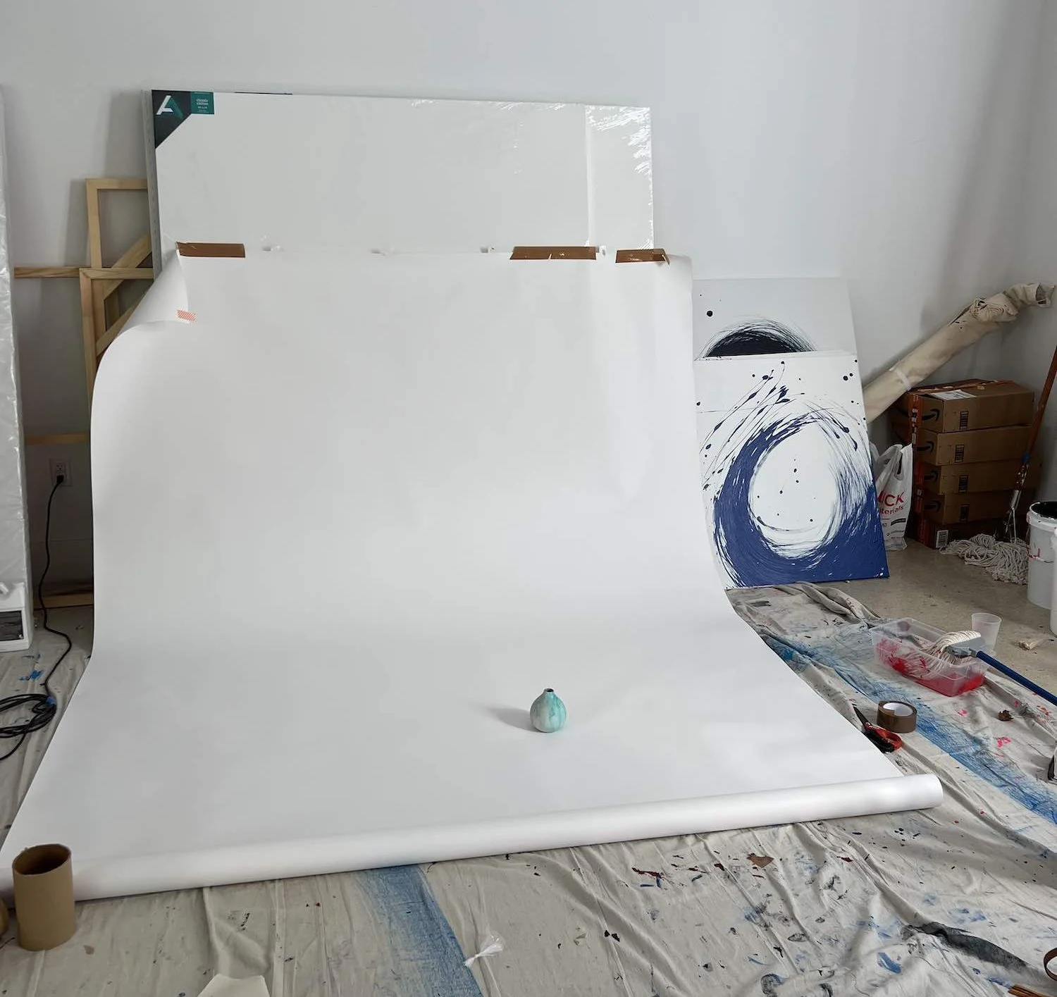 A clean white product photography surfaces setup in a studio with a small blue ceramic object placed in the center.
