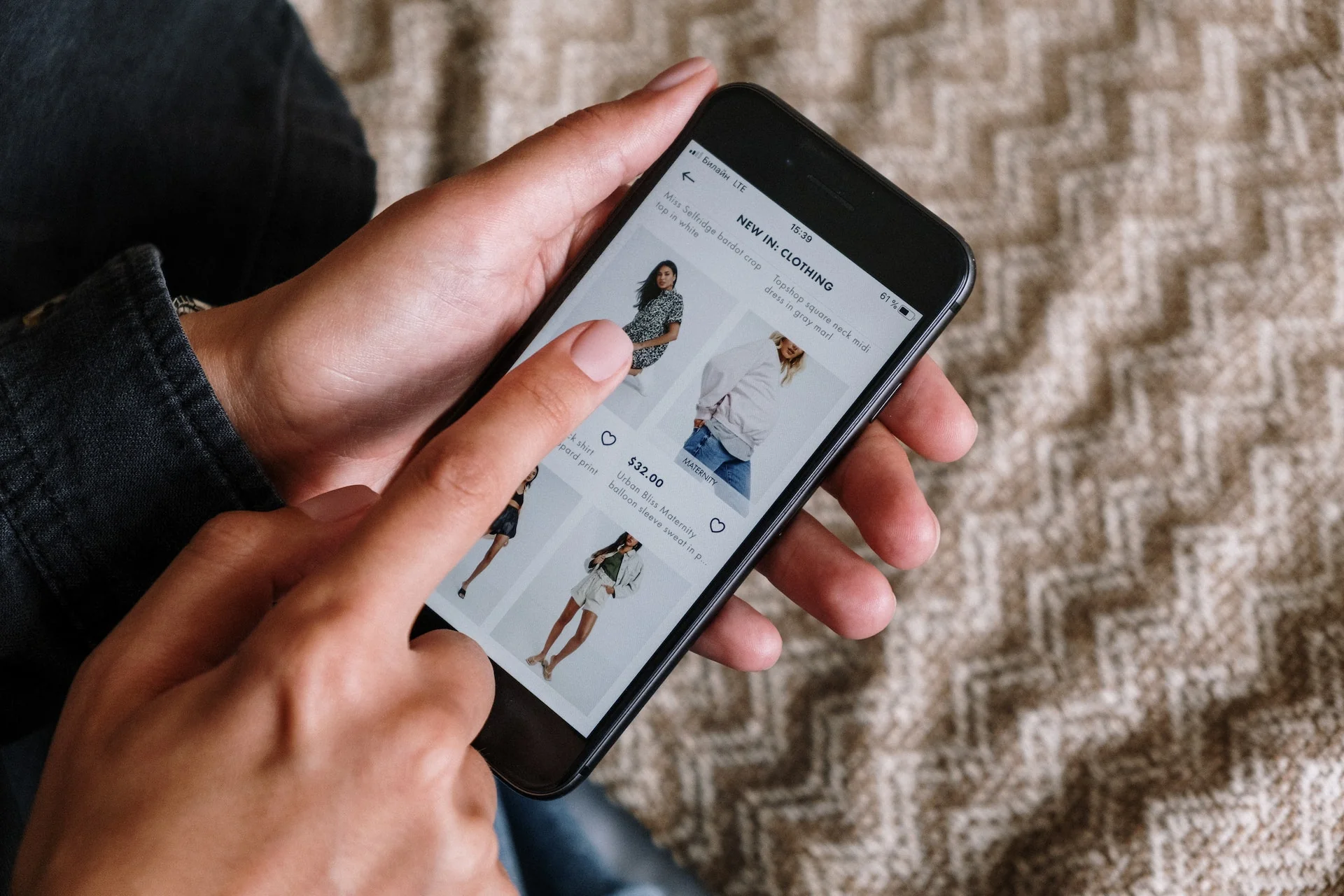A person browsing clothing items on an online store through a smartphone.