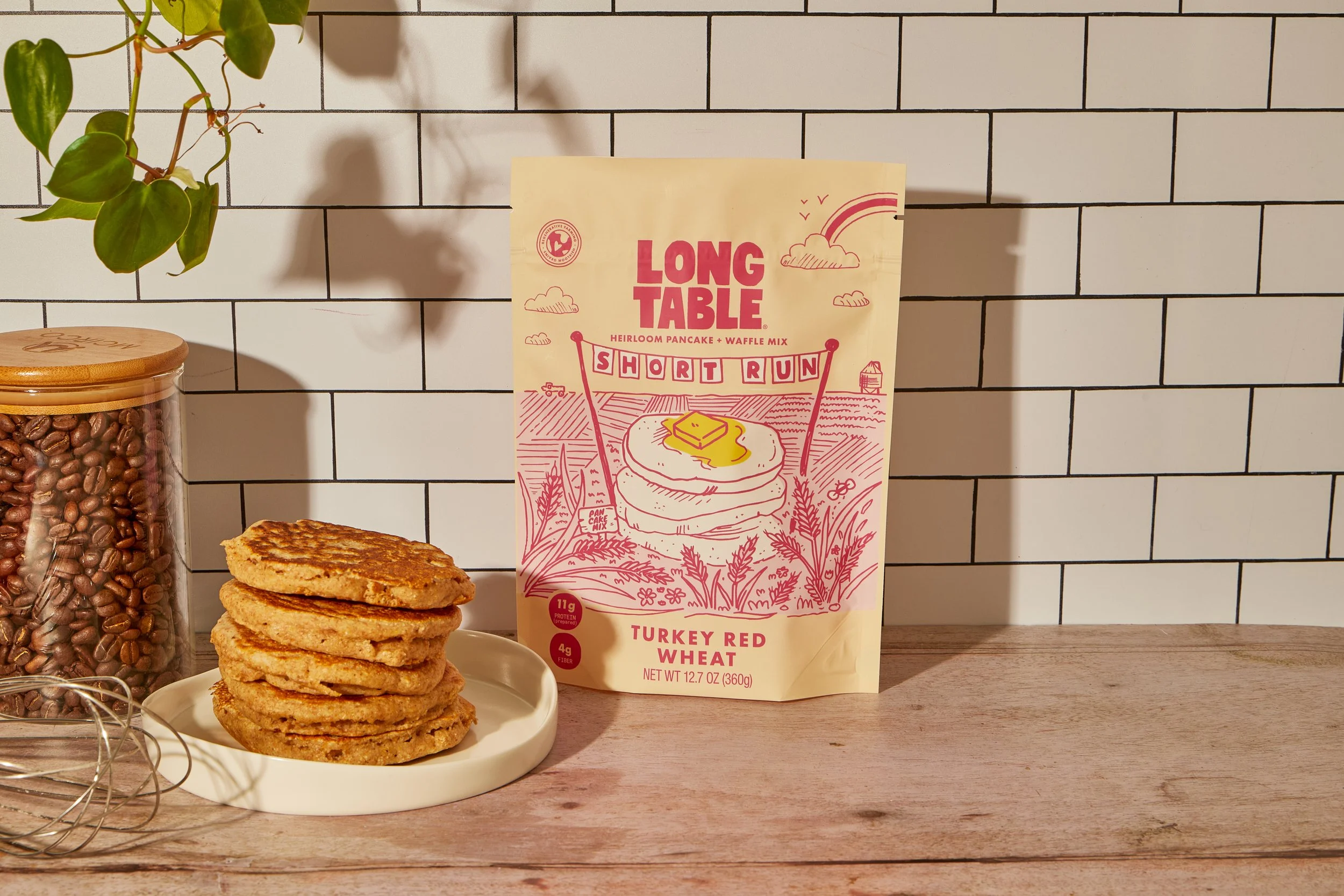 A straight-on shot of a stack of pancakes with a bag of pancake mix in the background.