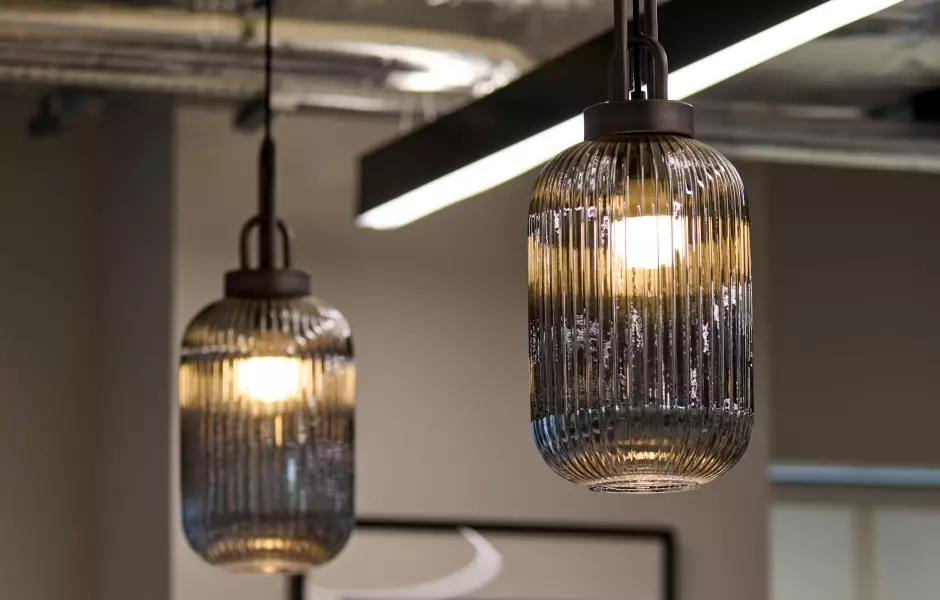 Close-up of stylish pendant lights with ribbed glass shades, casting a warm glow in a modern setting.