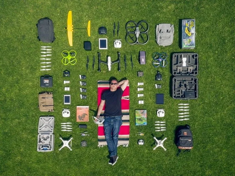Flat lay of drone photography gear with equipment and photographer on grass.