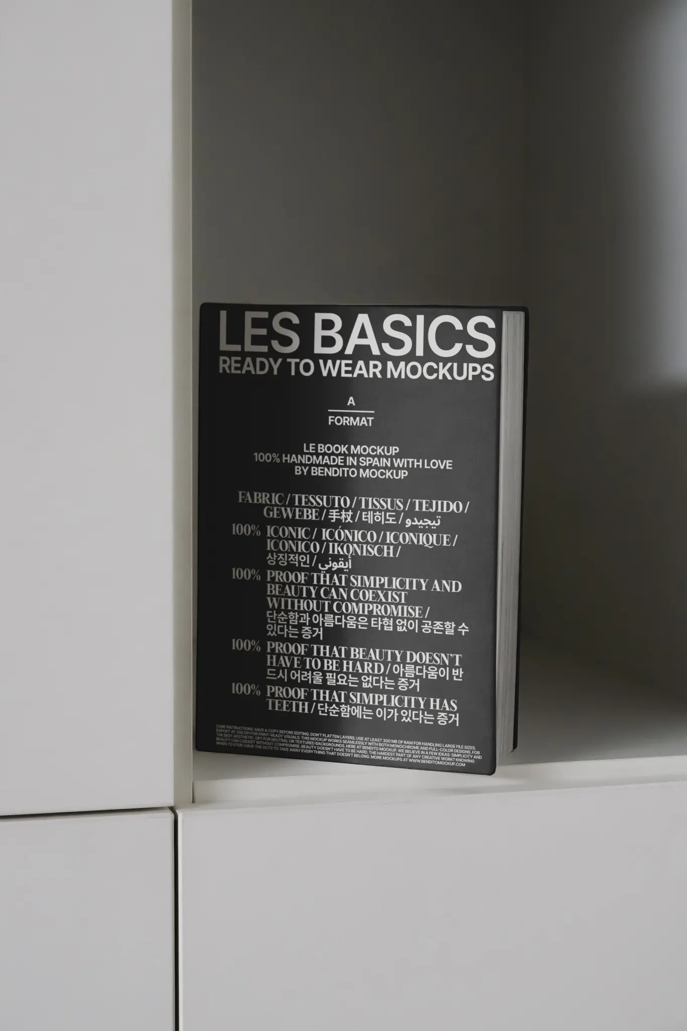 Black Les Basics hardcover book leaning against a white minimalist shelf in dark studio lighting – book product photography