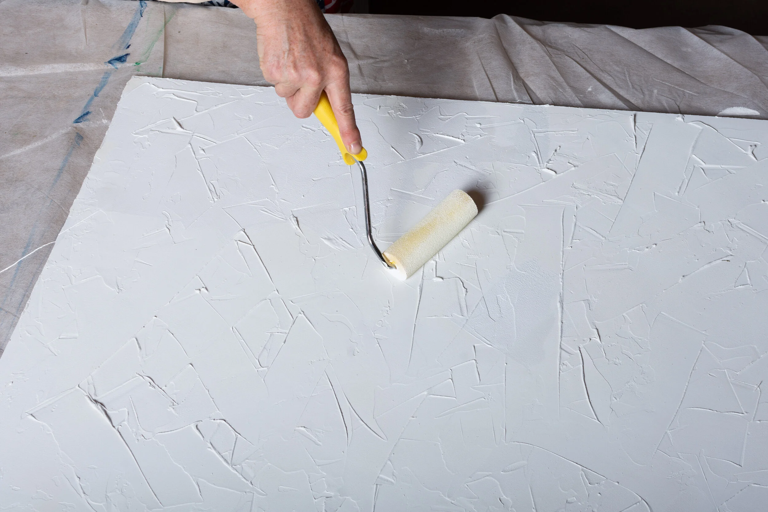 close up of a hand using roll brush for textured surface