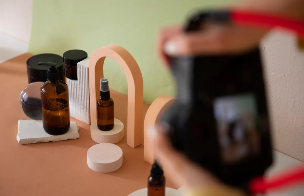 Camera photographing amber bottles arranged on geometric props