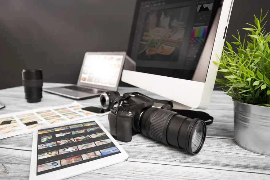 Desk with camera, tablet, laptop, and monitor