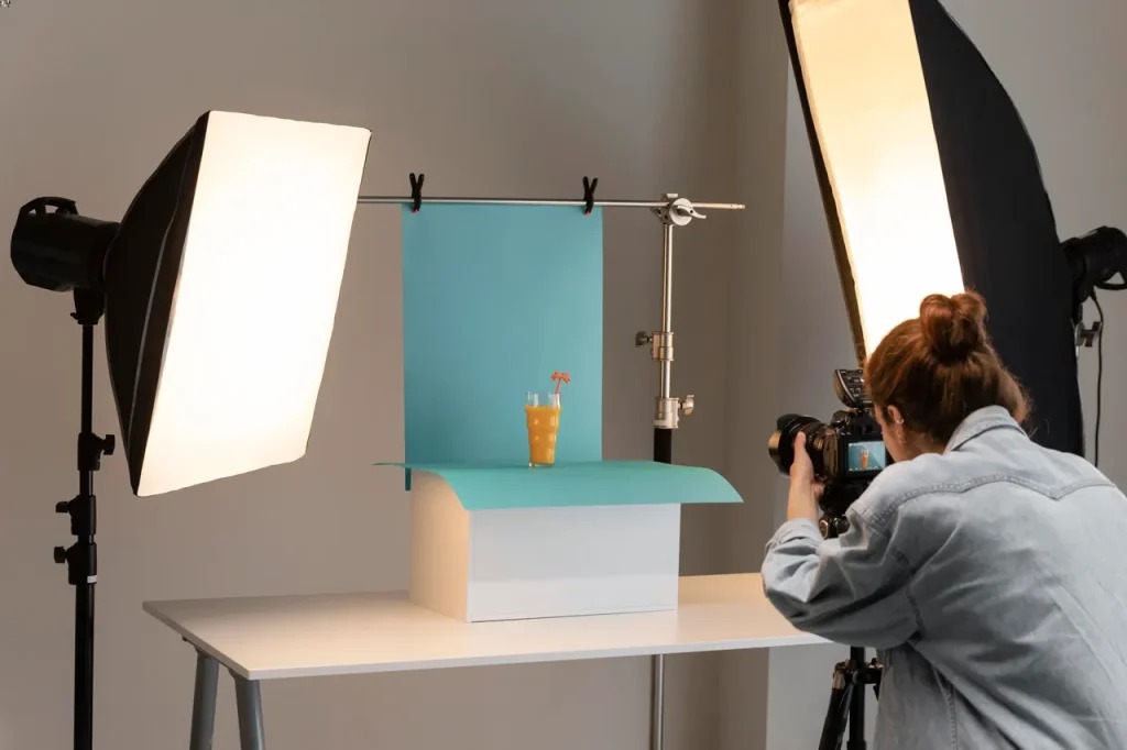 Photographer capturing a drink with studio lights and blue backdrop.