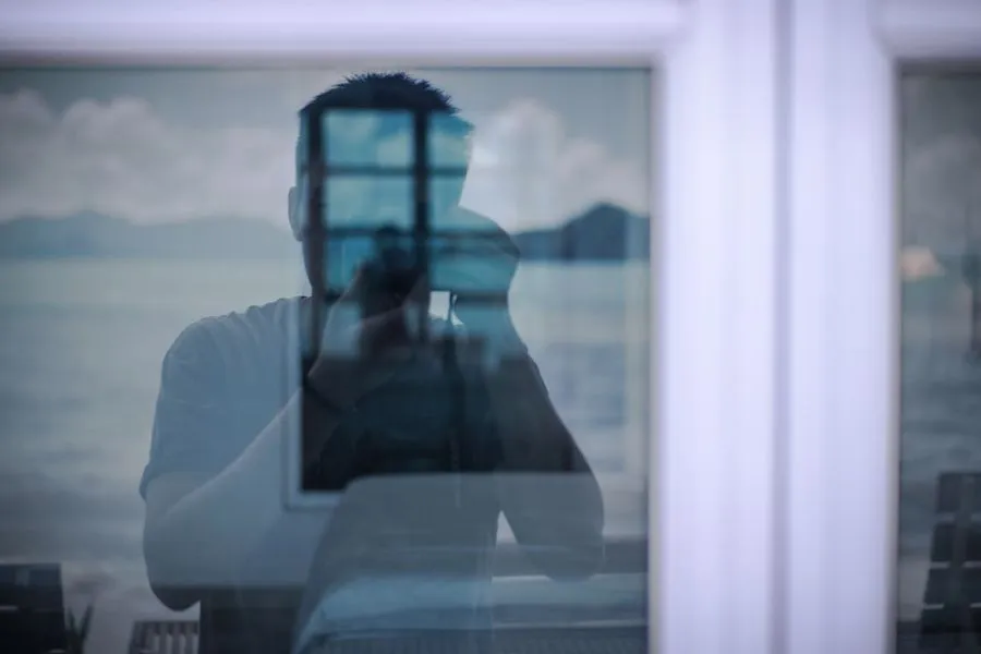 Photographer reflected in window glass holding a camera
