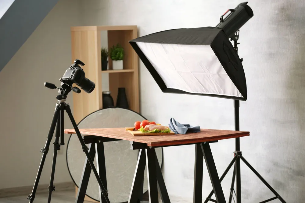 Professional food photography setup with camera on tripod and softbox light over a table with ingredients. 