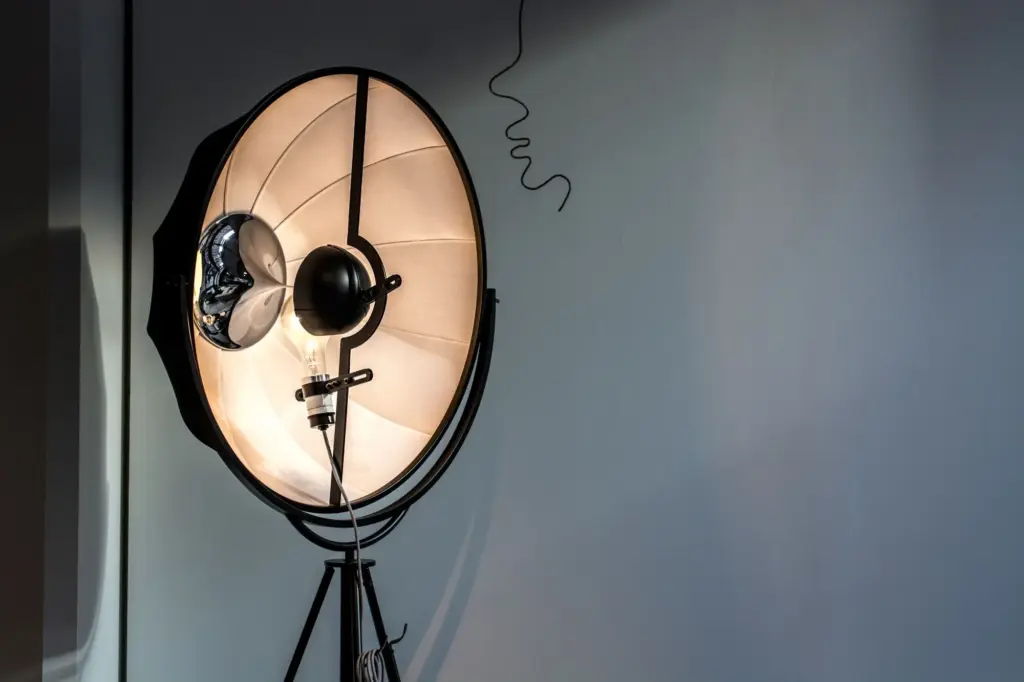 Studio light on tripod against gray wall.