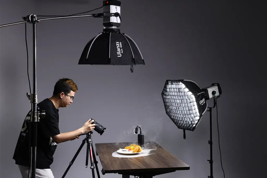 Photographer shooting a plated dish in a studio with professional lighting.