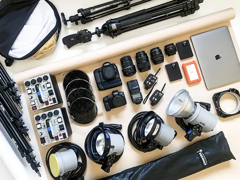 Product photography gear with cameras, lenses, strobes, softbox, tripods, and accessories.