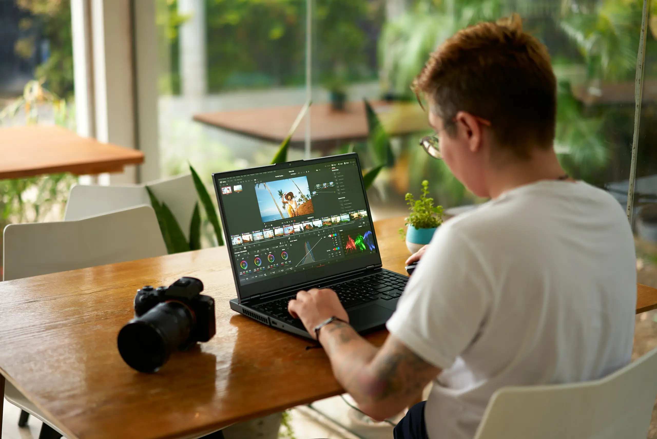 Person editing photos on a laptop with a camera beside them.